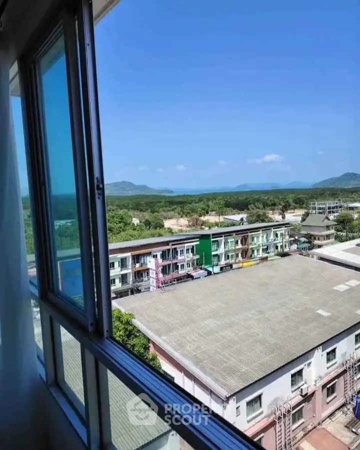 Stunning view from a high-rise window overlooking colorful buildings and lush greenery.