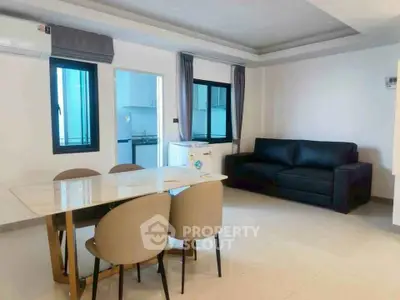 Modern living room with sleek dining area and cozy black sofa, adjacent to a compact kitchen.