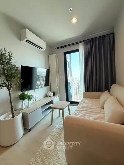 Modern living room with cozy beige sofa, wall-mounted TV, and balcony access in stylish apartment.