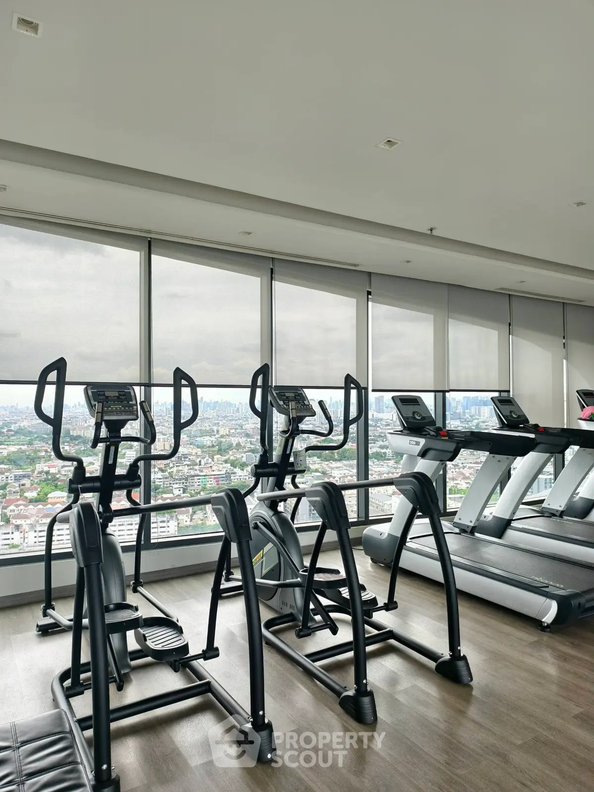 Modern gym with city view, featuring state-of-the-art exercise equipment and floor-to-ceiling windows.