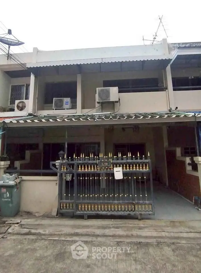 Charming two-story townhouse with gated entrance and air conditioning units.