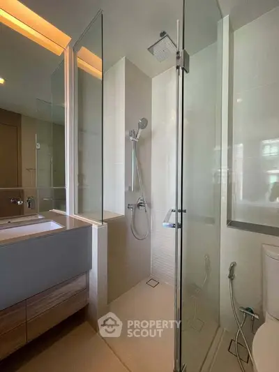 Modern bathroom with glass shower enclosure and sleek vanity in a contemporary apartment.