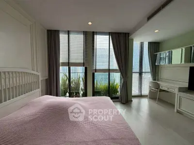 Spacious bedroom with large windows and modern decor in a high-rise apartment.