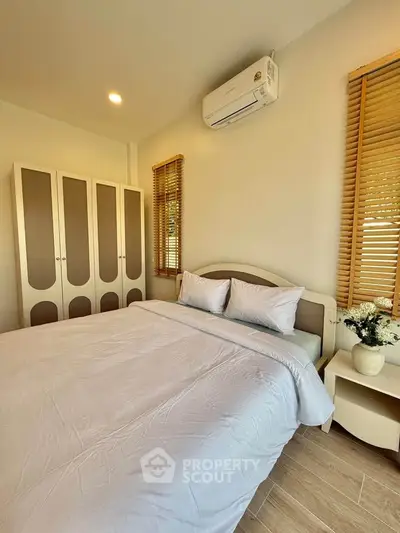 Cozy bedroom with modern decor, featuring a comfortable bed, stylish wardrobe, and air conditioning.