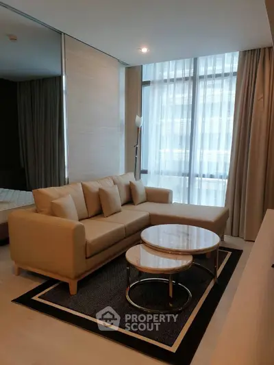Modern living room with stylish beige sofa and nested coffee tables in a bright apartment.