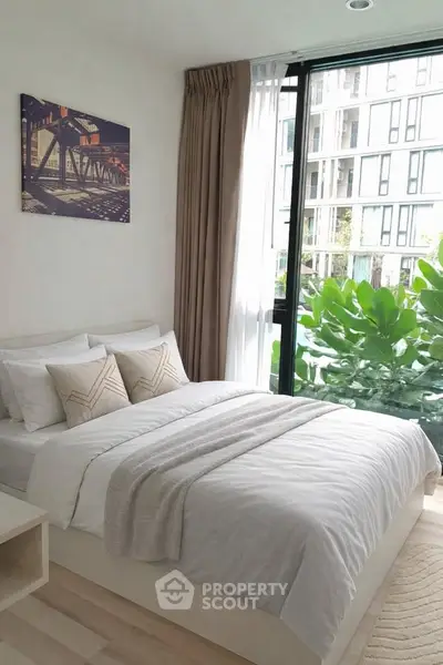 Modern bedroom with large window and lush greenery view, featuring cozy bedding and stylish decor.