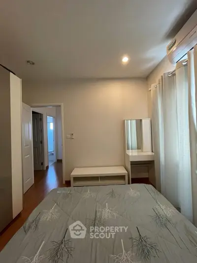 Cozy bedroom with natural light, featuring a stylish bed and a compact vanity area.