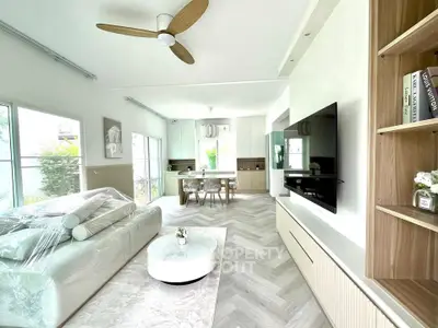 Modern living room with stylish decor and open layout, featuring a large TV and elegant furniture.