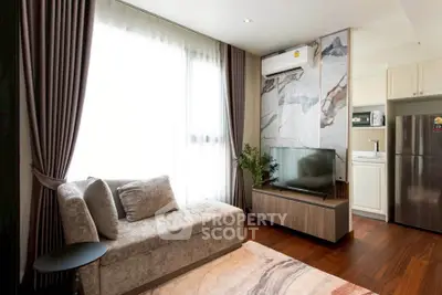 Modern living room with elegant decor and natural light, featuring a cozy sofa and sleek TV setup.