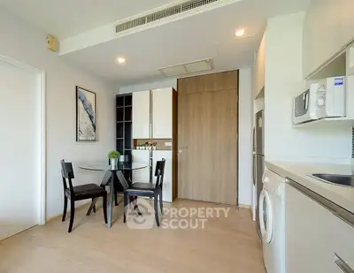 Modern kitchen with dining area, featuring washing machine and microwave, in a stylish apartment.