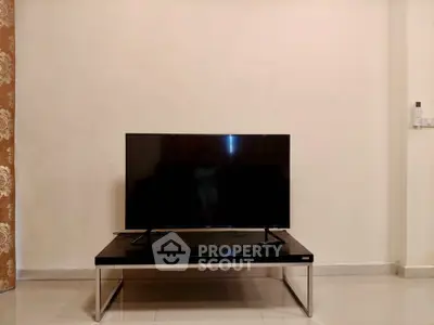 Minimalist living room with modern TV setup on sleek stand, perfect for entertainment.