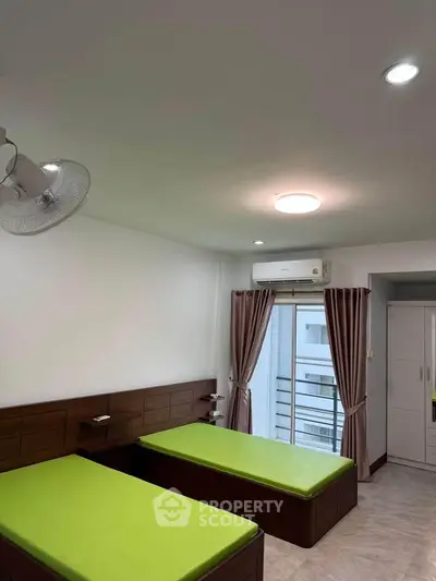 Spacious bedroom with twin beds, air conditioning, and balcony access in modern apartment.