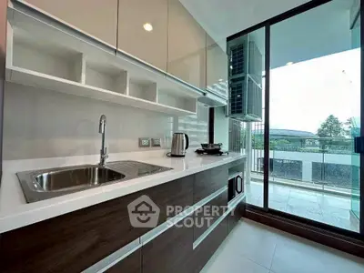Modern kitchen with sleek cabinetry and balcony view