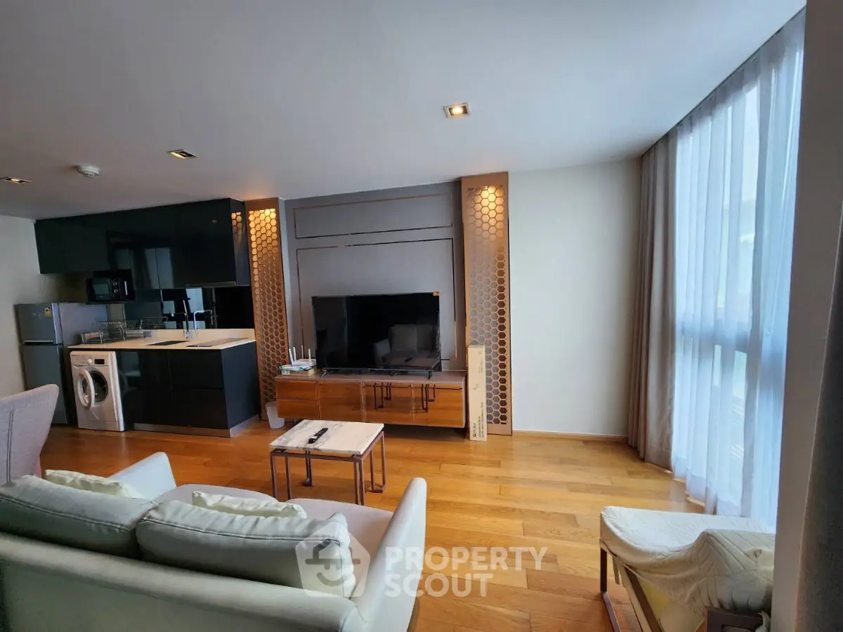 Modern living room with open kitchen, featuring sleek appliances and stylish decor.