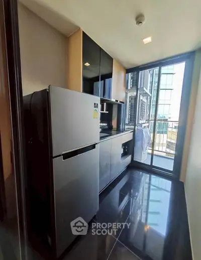 Modern kitchen with sleek appliances and balcony view in high-rise apartment