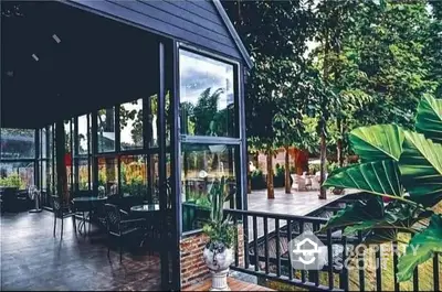 Charming outdoor patio with lush garden views and modern glass architecture, perfect for relaxation and entertaining.