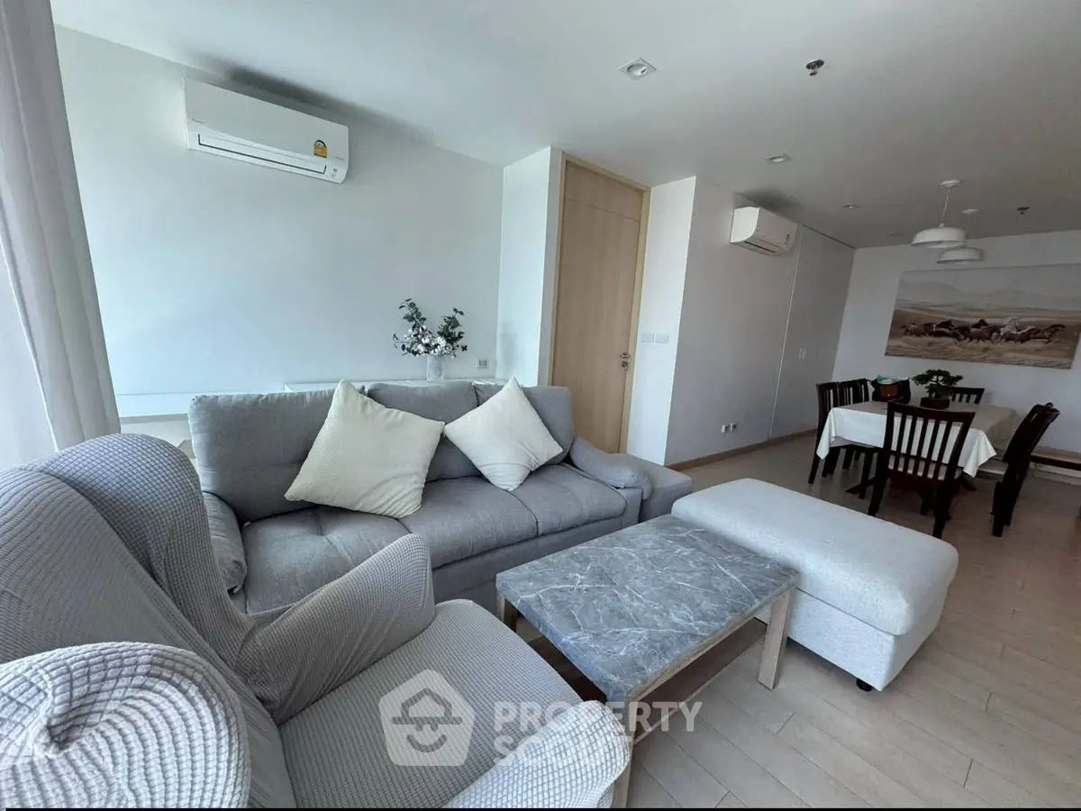 Modern living room with stylish furniture and dining area in open layout apartment.