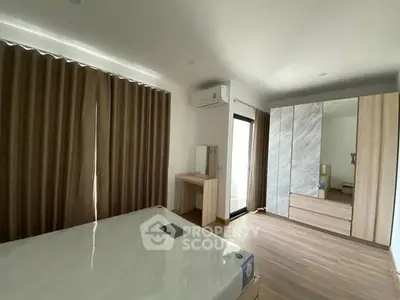 Spacious modern bedroom with large mirrored wardrobe and natural light.