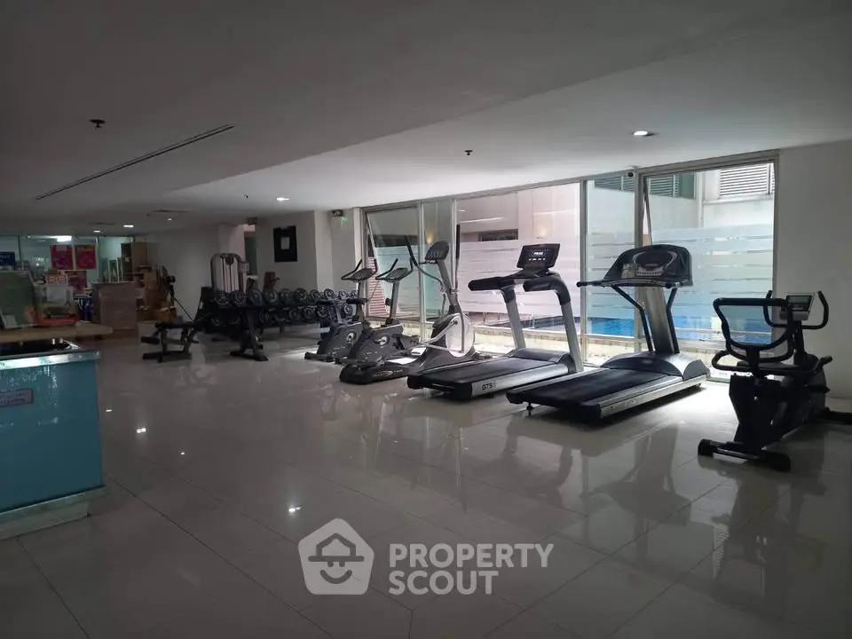 Spacious gym with modern exercise equipment and large windows for natural light.