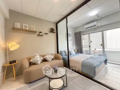 Modern studio apartment with cozy living area and stylish bedroom separated by glass partition.