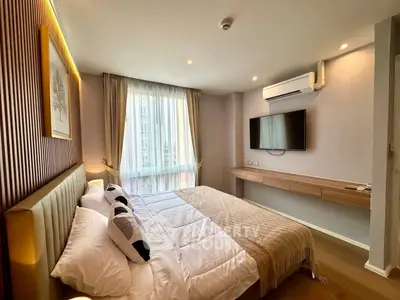 Modern bedroom with stylish decor and natural light, featuring a wall-mounted TV and air conditioning.