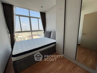 Modern bedroom with large window offering stunning city views and ample natural light.