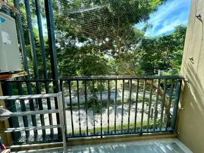 Charming balcony with lush greenery view and ample sunlight, perfect for relaxation and outdoor enjoyment.