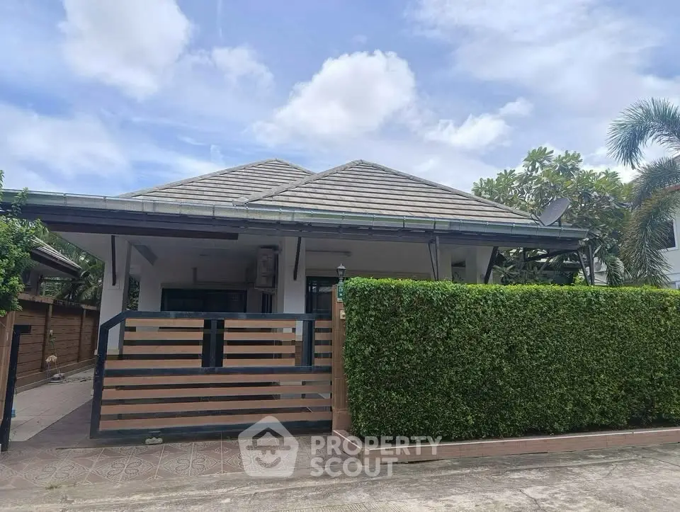 Charming single-story home with lush greenery and modern fence in serene neighborhood.