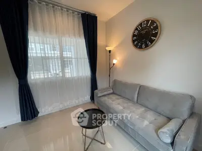 Cozy living room with modern gray sofa and stylish clock on the wall.