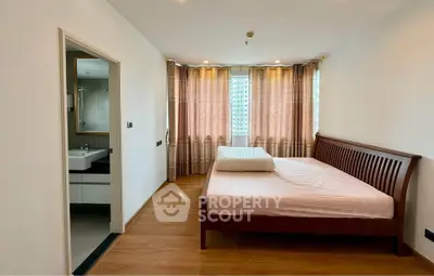 Spacious bedroom with wooden flooring and ensuite bathroom in modern apartment