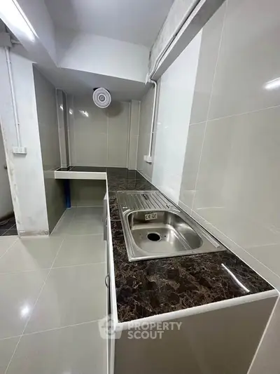 Modern kitchen with sleek countertops and stainless steel sink in a contemporary apartment.