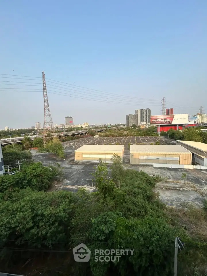 Expansive urban view showcasing industrial buildings and lush greenery under a clear blue sky.
