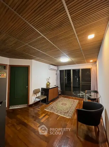 Charming living room with wooden ceiling and floor, featuring a cozy seating area and large window.