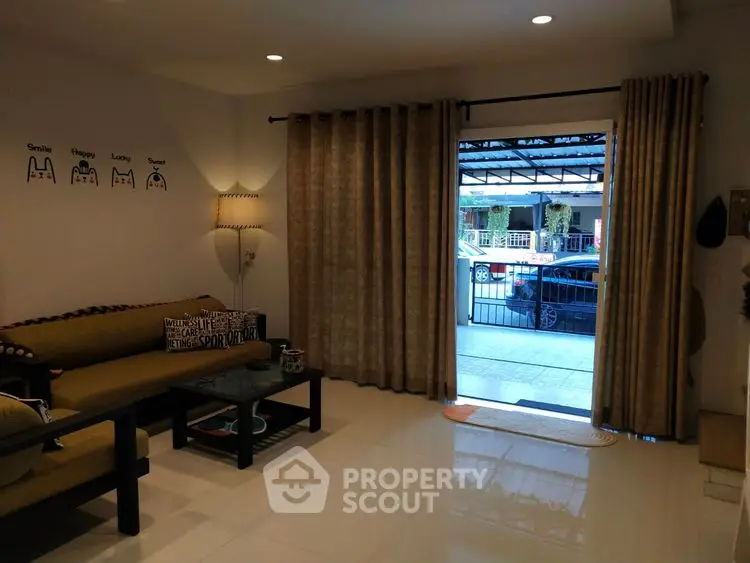 Cozy living room with modern decor and large window overlooking driveway