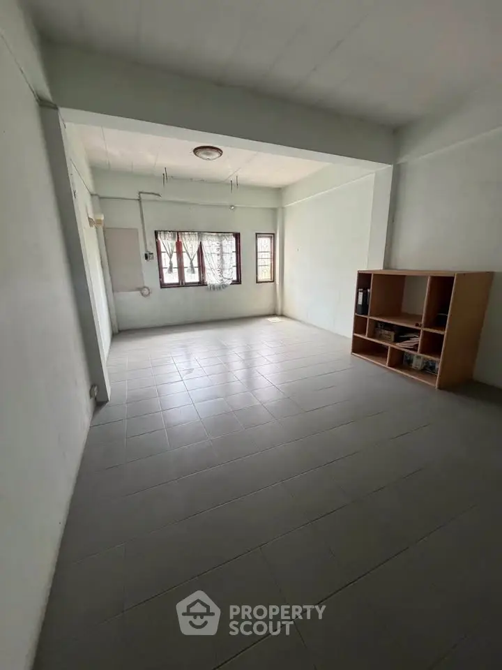 Spacious empty room with tiled flooring and natural light, ideal for customization.