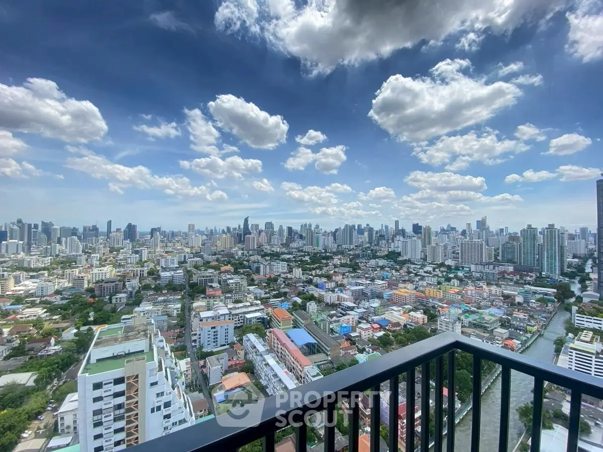Stunning cityscape view from high-rise balcony with vibrant skyline and fluffy clouds.