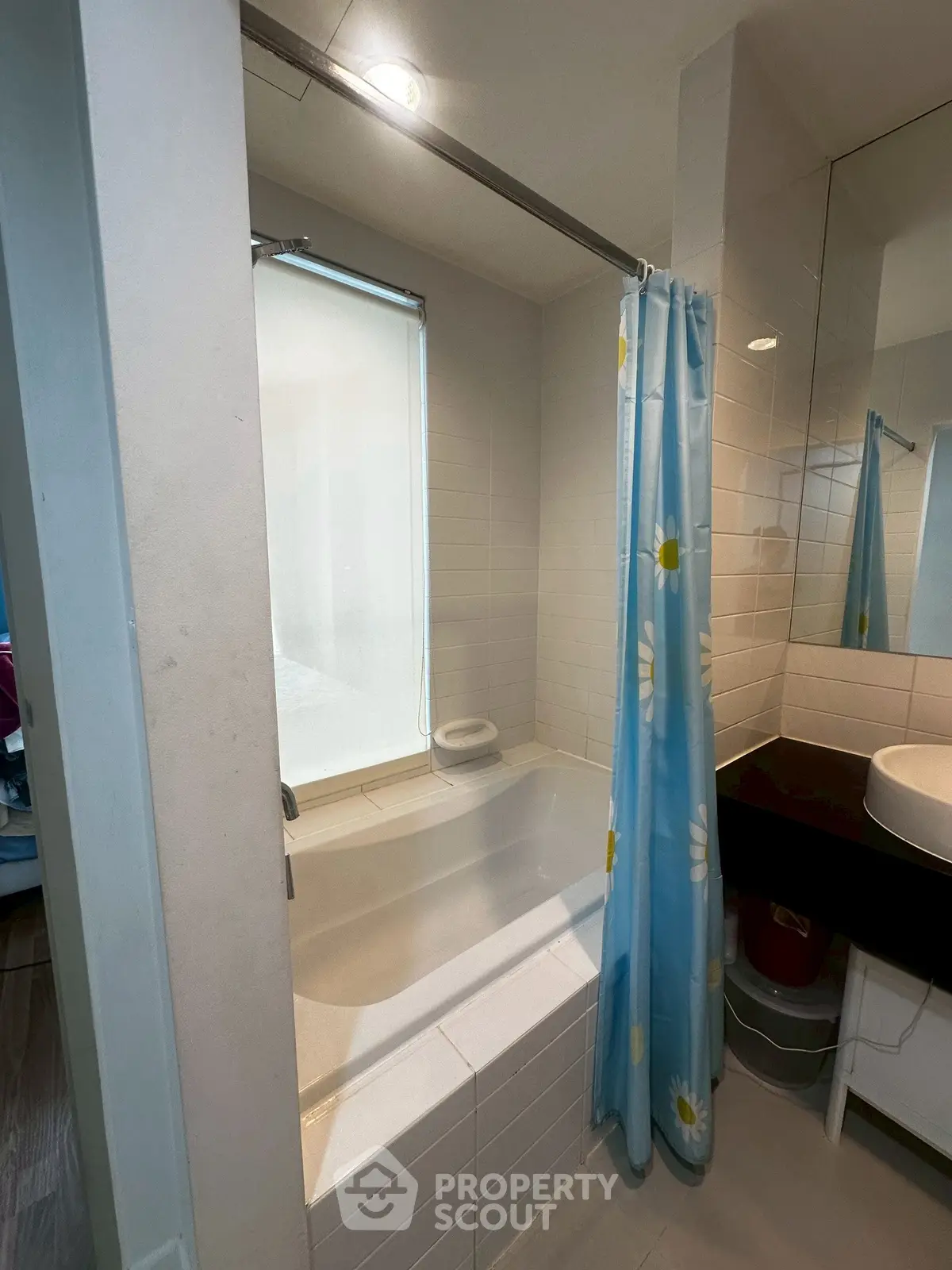 Charming bathroom with a cozy bathtub and floral shower curtain, perfect for relaxation.