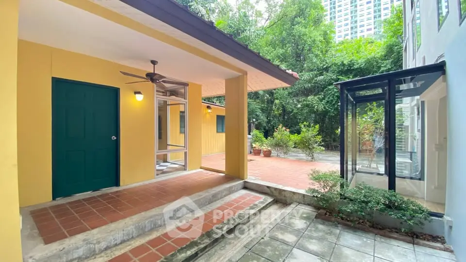 Charming yellow exterior with lush greenery and modern glass extension