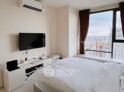 Modern bedroom with city view, featuring sleek furniture and large windows for natural light.