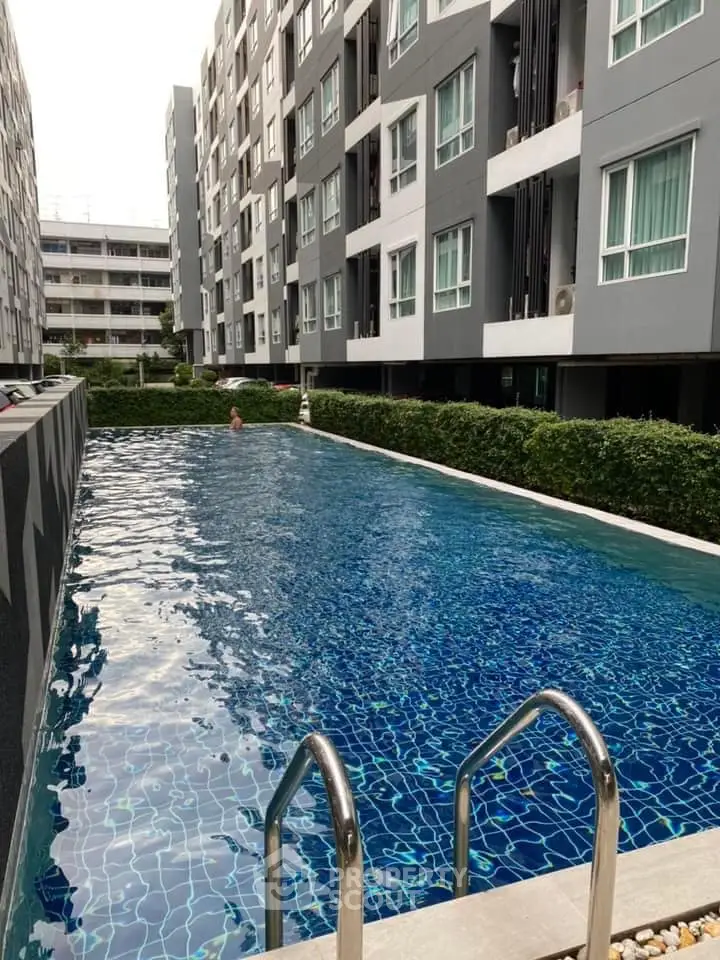 Modern apartment complex with inviting outdoor swimming pool and lush greenery.