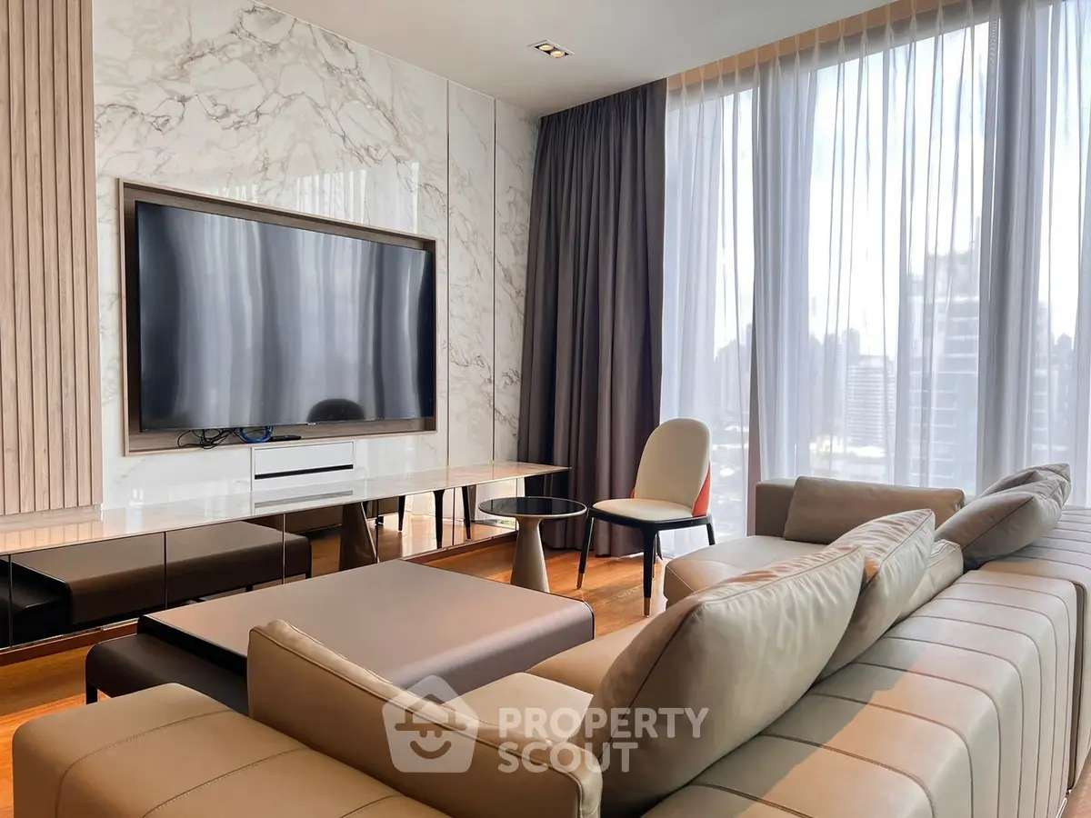 Luxurious modern living room with large TV and elegant furnishings, featuring floor-to-ceiling windows with city views.