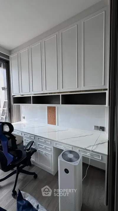 Modern study room with built-in cabinets and sleek desk in a bright apartment.