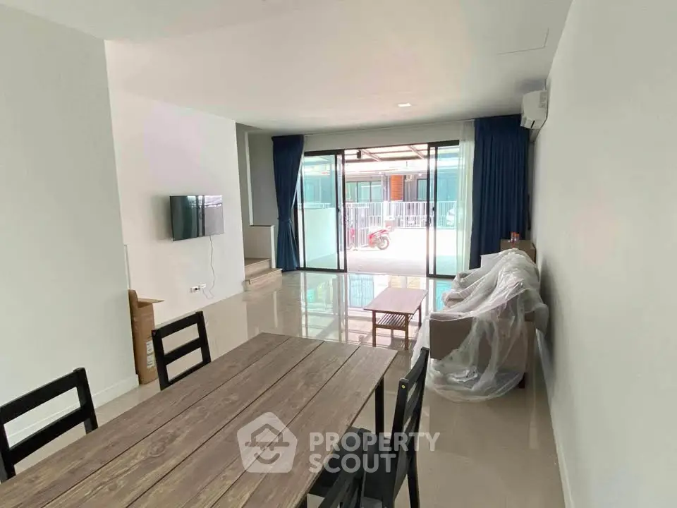 Modern living room with dining area and large glass doors leading to balcony.
