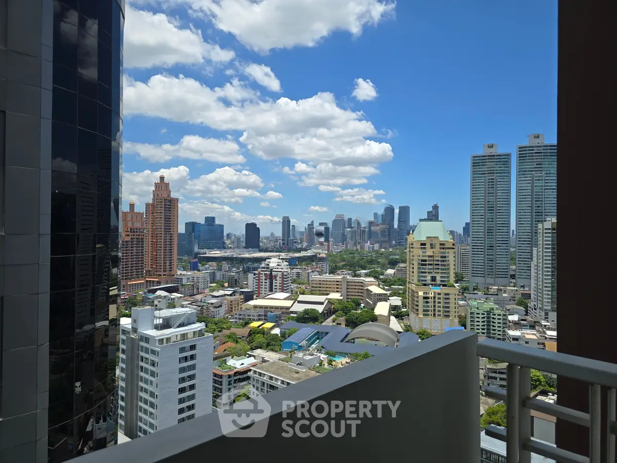 Stunning cityscape view from a high-rise balcony showcasing urban skyline and blue skies.
