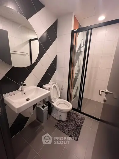 Modern bathroom with sleek design, featuring a glass shower enclosure and stylish black and white tiles.