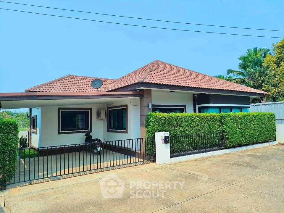 Charming single-story house with manicured hedges and tiled roof in a serene neighborhood.