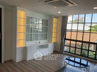 Spacious living room with large windows and modern built-in shelving in a bright apartment.