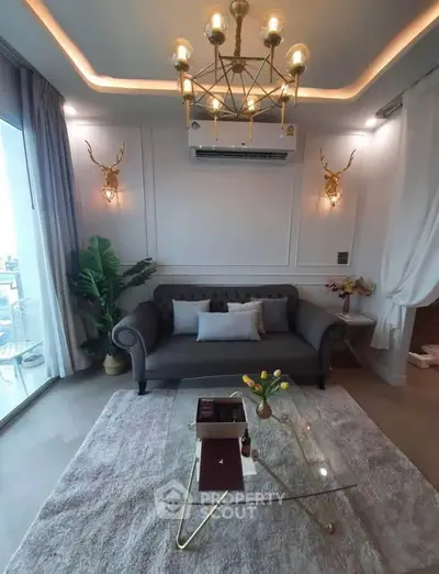 Luxurious living room with elegant decor and modern chandelier, featuring a cozy sofa and glass coffee table.