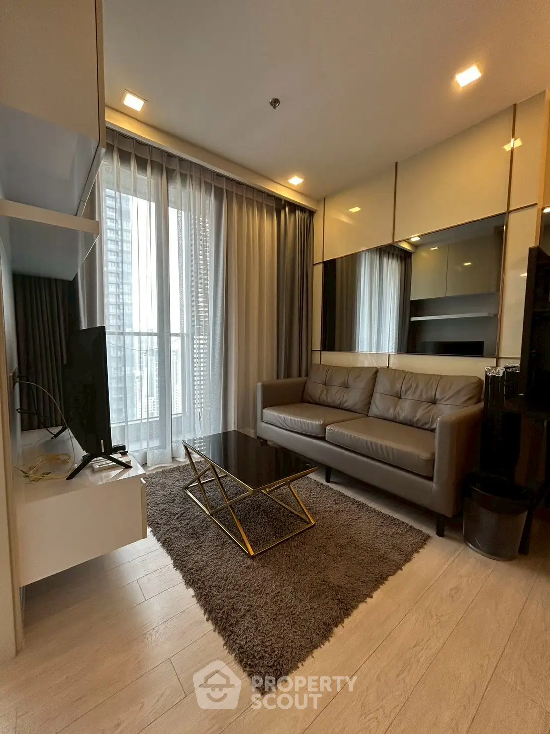 Modern living room with sleek furniture and floor-to-ceiling windows in a high-rise apartment.