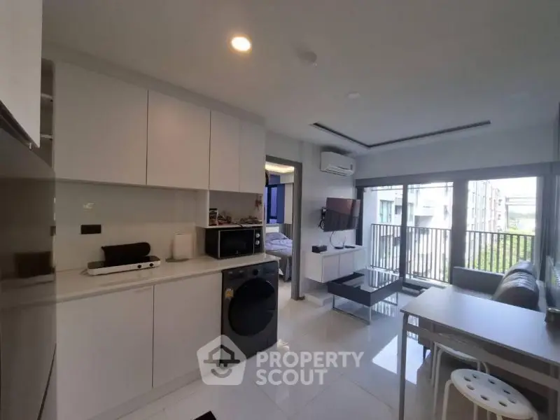 Modern open-plan living room with kitchen and balcony view in stylish apartment.